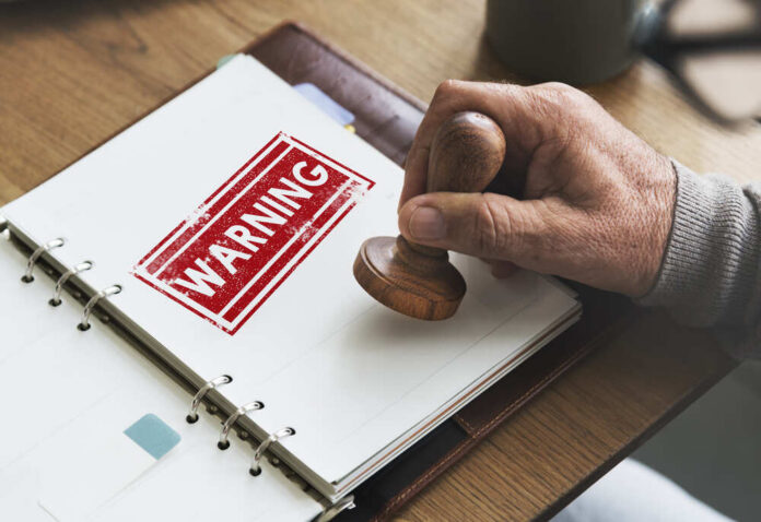 Caution,Denied,Pending,Rejected,Secret,Warning,Concept A hand applying a warning stamp on a document