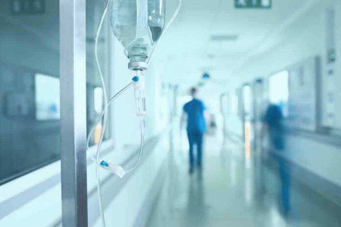 shutterstock_528854752-1 Hospital corridor with IV drip and healthcare worker.