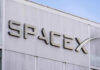 BOOM! SpaceX Mania Makes Him a Trillionaire?! SpaceX building logo against blue sky.