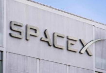BOOM! SpaceX Mania Makes Him a Trillionaire?! SpaceX building logo against blue sky.