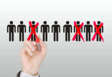97,000 Job Cuts Blamed On THIS Again! Hand crossing out stick figures with a red marker.