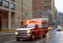 Ambulance with flashing lights driving on a wet city street