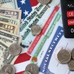 ALERT: Social Security Cliff Moved Up Various denominations of U.S. currency and financial documents on a flag background