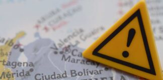 A close-up of a map of Venezuela with a yellow warning sign