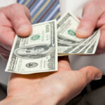 Two hands exchanging cash bills