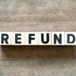 Wooden blocks spelling the word 'REFUND' on a wooden surface