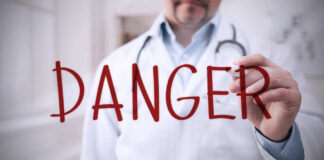Doctor writing danger on transparent screen
