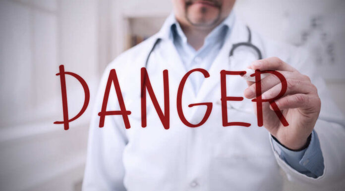 Doctor writing danger on transparent screen