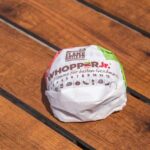 Whopper Promise Sparks Industry Jitters A wrapped Whopper Jr. burger resting on a wooden table