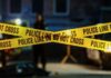 VIDEO: Ambush Leaves Cop, Family Dead Police tape marking a crime scene with blurred figures in the background