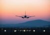 An airplane approaching for landing against a colorful sunset sky