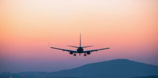 An airplane approaching for landing against a colorful sunset sky