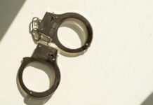 A pair of metallic handcuffs resting on a light surface