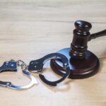 Fraudster Returns To Prison — Why So Little? Gavel and handcuffs on wooden table