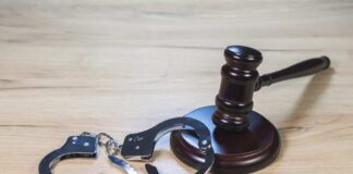 Gavel and handcuffs on wooden table