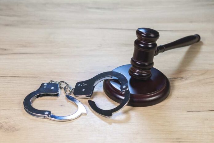 Gavel and handcuffs on wooden table