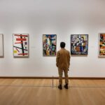 Museum Alarm Fails — Thieves Walk Out Rich A person standing in an art gallery, observing various modern art pieces on the wall