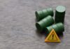 Antitrust Dogs Circle Big Oil Four green barrels and a warning sign on a wooden surface