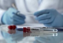 Ebola test tubes on lab table with gloved scientist in background
