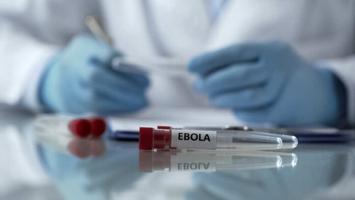 Ebola test tubes on lab table with gloved scientist in background