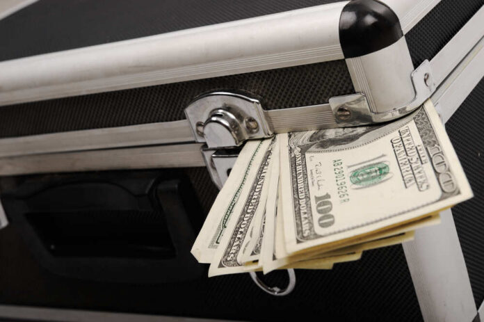 Money,Coming,Out,Of,Suitcase Airplane interior with passengers seated mid-flight.