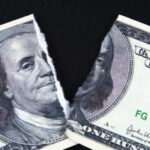 Alex Jones’ $50M Slashed — Here’s Why A torn hundred dollar bill featuring Benjamin Franklin