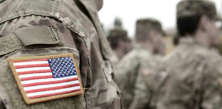 U.S. soldiers in camouflage uniforms with American flag patch.