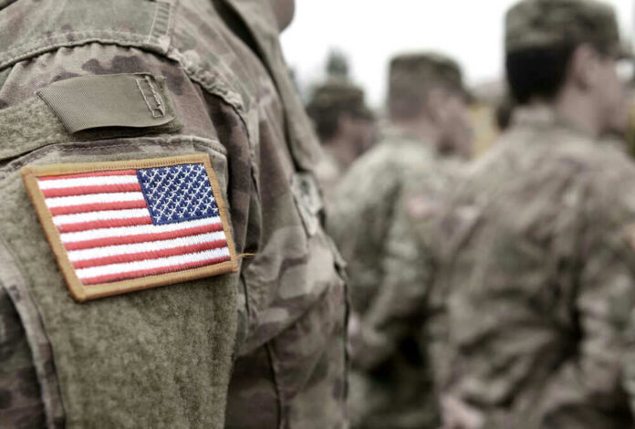 shutterstock_18369768851 U.S. soldiers in camouflage uniforms with American flag patch.