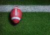 Football player kneeling on the field with a helmet beside them