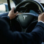 Burning Car Trap? Tesla Admits Alarming Flaw Person driving a Tesla car steering wheel