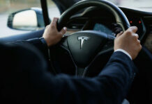 Burning Car Trap? Tesla Admits Alarming Flaw Person driving a Tesla car steering wheel
