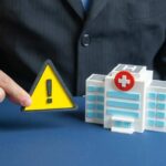 11,000 Sick — Lettuce Bombshell Grows A business professional holding a warning sign next to a model of a hospital