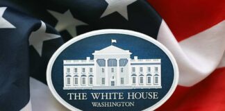 Press podium with the White House sign and an American flag in the background