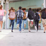 Children running with backpacks outside a school building.