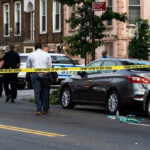 Police and crime scene tape on city street.