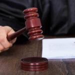 Judges hand holding gavel next to documents.