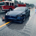 Car crash with a Tesla on a rainy highway.
