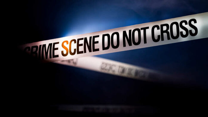 Police tape reading 'CRIME SCENE DO NOT CROSS' in a dark setting
