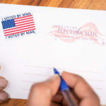 Hands addressing an official election mail envelope