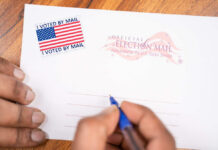 BUSTED! Postal Worker DUMPS Election Ballots Hands addressing an official election mail envelope