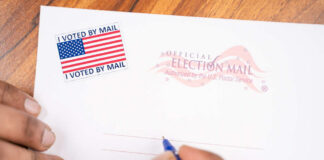 Hands addressing an official election mail envelope
