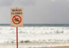 Sign indicating the beach is closed with a no swimming symbol
