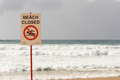 Sign indicating the beach is closed with a no swimming symbol