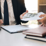 401(k) Shock: Record Smashes Expectations Two individuals engaged in a business transaction involving money and documents