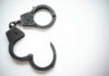 Shocking Arrest: 11-Year-Old Booked For Murder Open metal handcuffs on white background.