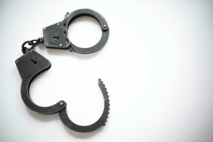 Open metal handcuffs on white background.