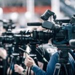 Salad Parasite Explodes – Thousands Sickened Broadcast cameras on tripods at a press event
