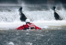 VIDEO: Deadly Canyon Deluge Triggers Frantic Airlifts Rescuer in red gear navigating turbulent water near a waterfall