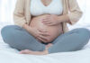 Pregnant woman sitting crosslegged on bed