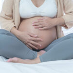 Pregnancy Rewrite Ignites Firestorm Pregnant woman sitting crosslegged on bed